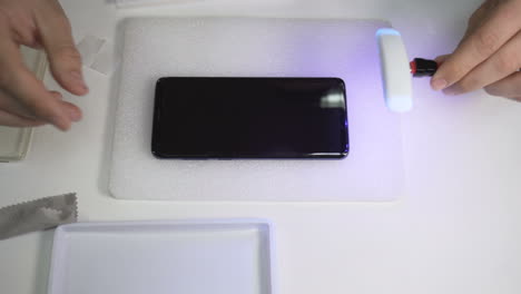 man uses uv flashlight to protect the screen of a smartphone