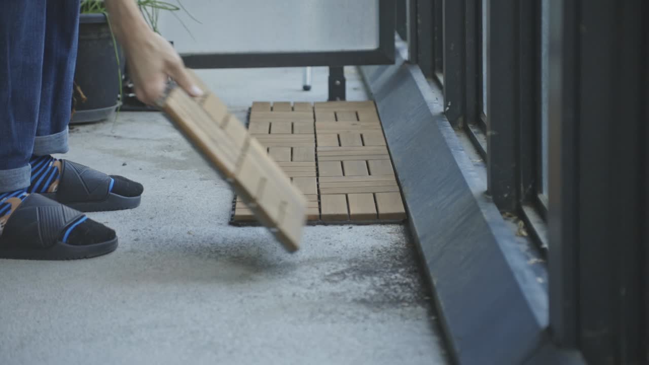 Nærbillede af en person, der lægger sammenlåselige terrassefliser på en veranda
