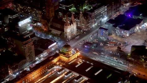 Lapso-De-Tiempo-Nocturno-Con-La-Estación-De-Flinders,-La-Catedral-De-Paul-Y-La-Plaza-De-La-Federación-De-La-Ciudad-De-Melbourne-Llena-De-Movimientos-De-Peatones,-Tráficos-Y-Tranvías-Desde-La-Torre-Eureka-En-Bucle