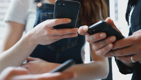 close up of businesswomen using mobile phones in modern office