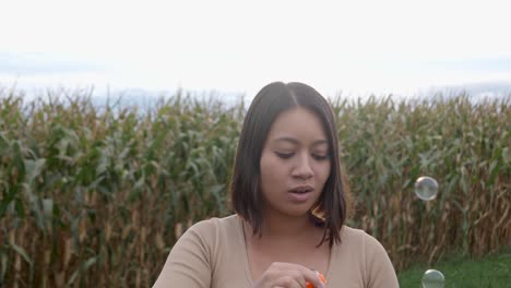 mujer asiática divirtiéndose al aire libre y soplando pompas de jabón