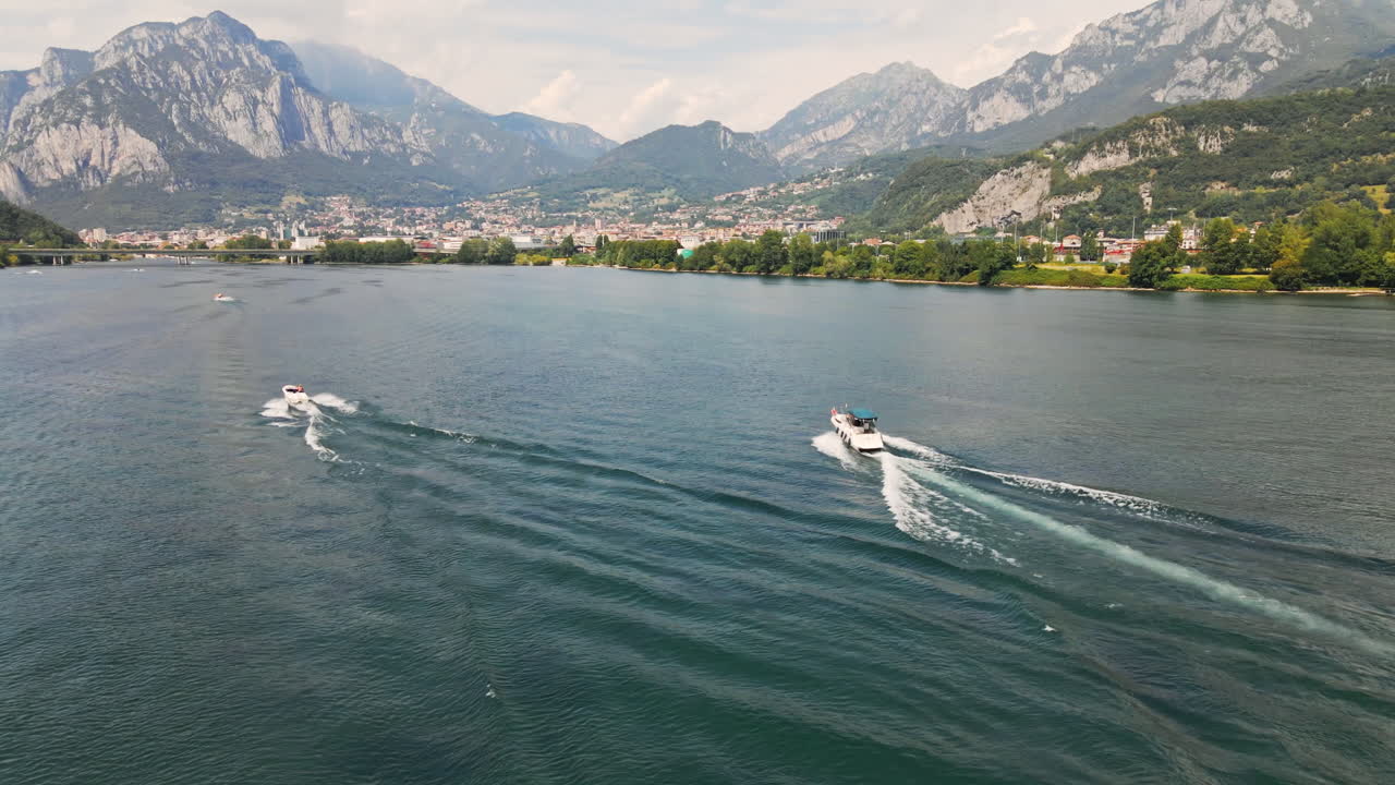 paisaje pintoresco con montañas y barcos navegando en el agua en el lago de como, italia durante el verano - tiro estático de drones aéreos