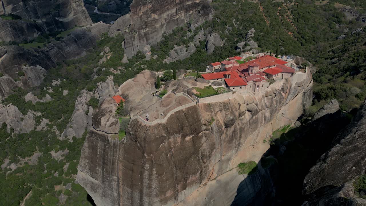 Aerial pan across Roussanou Monastery perched high above valley in Meteora, Greece