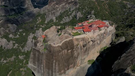 Aerial pan across Roussanou Monastery perched high above valley in Meteora, Greece