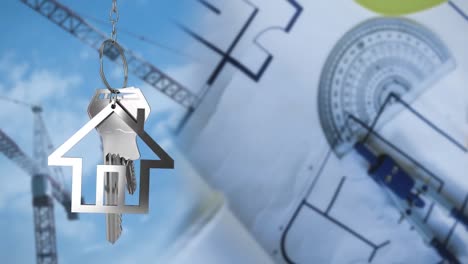 llaves de la casa y llaves colgando sobre dibujos arquitectónicos y grúas en el fondo