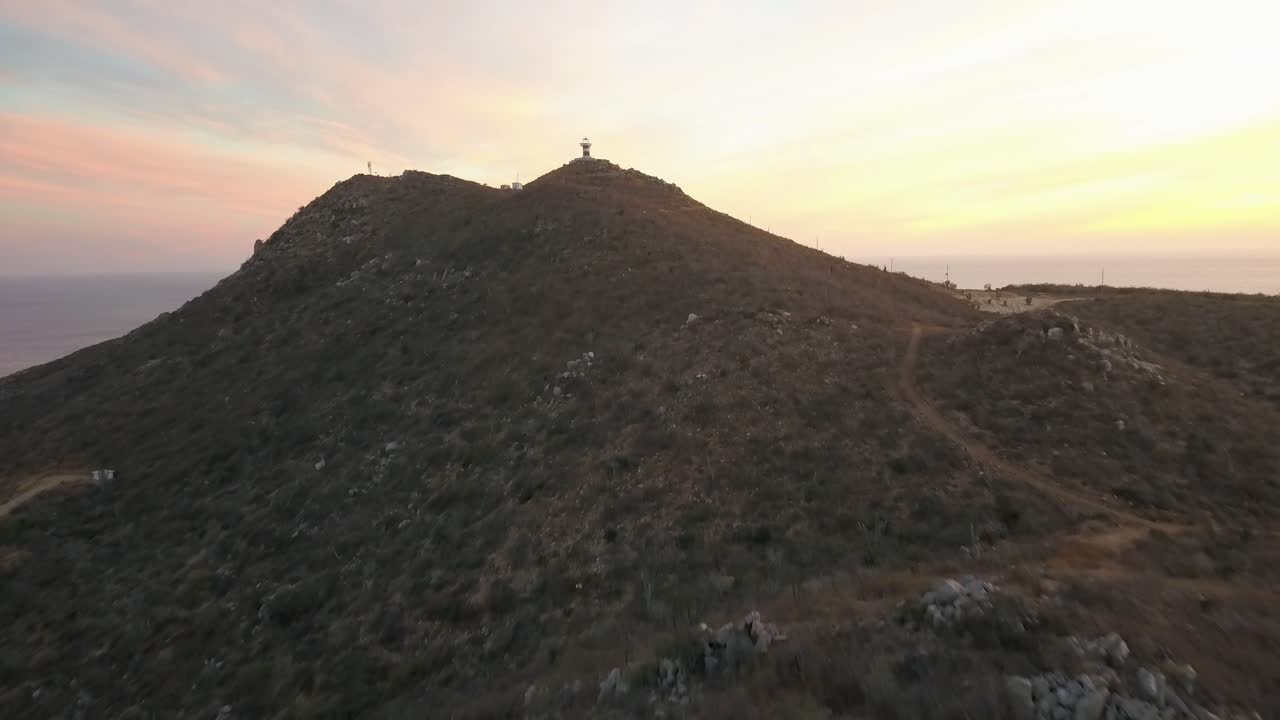 Aerial approaching modern lighthouse at Cabo Falso, Cabo San Lucas. Beautiful sunset tones.
