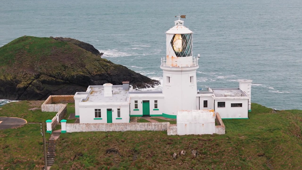 Faro di Strumble Head con faro a torre lampeggiante che domina la frastagliata costa del Pembrokeshire