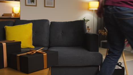 close up of man putting gift wrapped presents on table in lounge at home