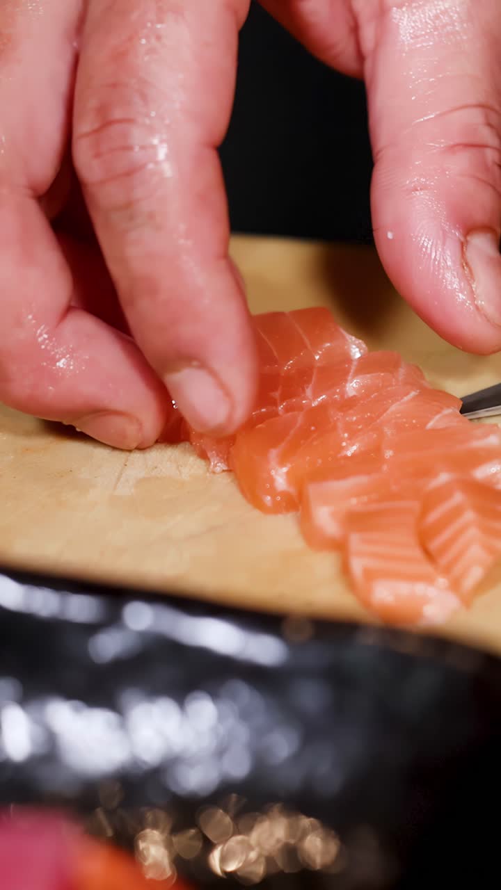 Nahaufnahme von Händen, die mit einem scharfen Messer rohen Lachs für japanisches Sashimi schneiden.