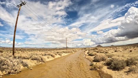 water from unseasonably heavy rains fills the usually dry cache creek, mojave desert riverbed - aerial flyover