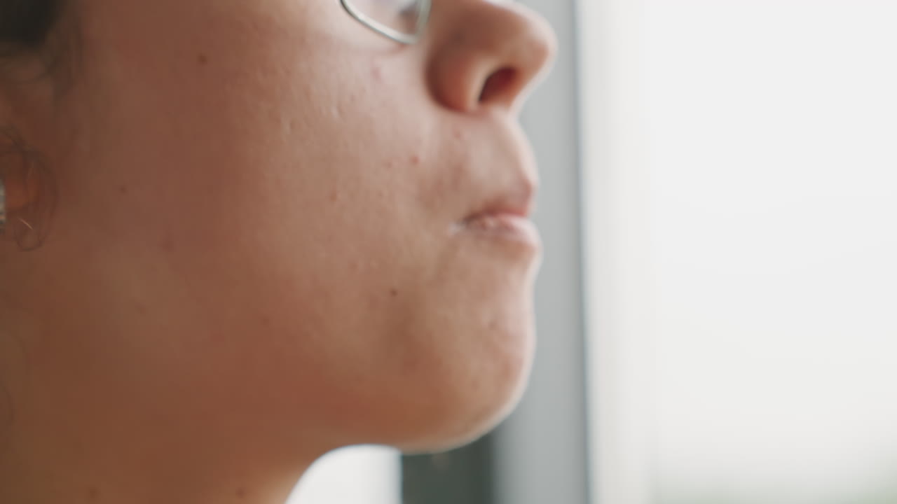Mujer multirracial, huésped de hotel, probando un primer plano de labios y barbilla. Estudiante de cocina prueba textura y sabor con una galleta, masticación sutil, taza de porcelana cerca de la boca, perfil introspectivo, suave luz de ventana, sensorial