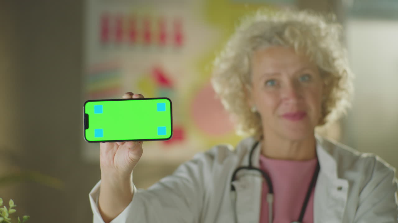 녹색 화면 을 가진 스마트폰 을 들고 있는 의사