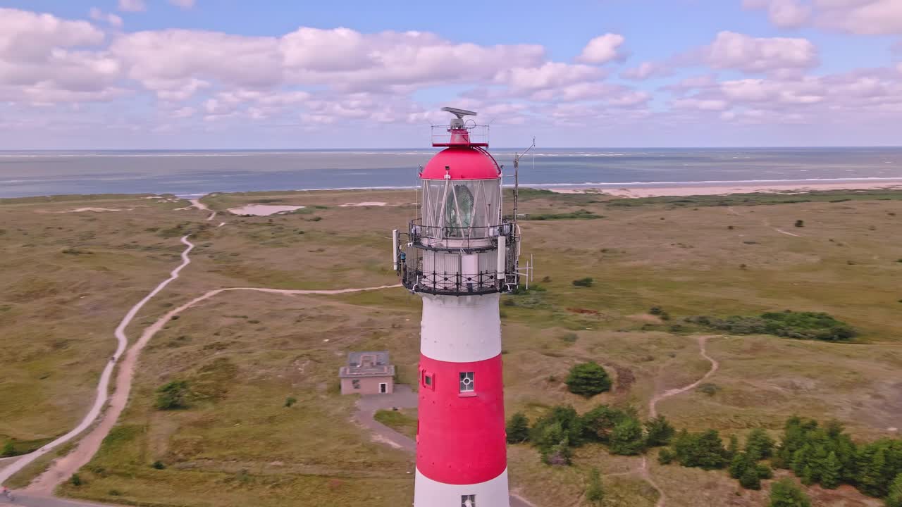 Dronebillede af Ameland-fyrtårnet i Holland, der viser klitter, kystlinje og omkranset af træer