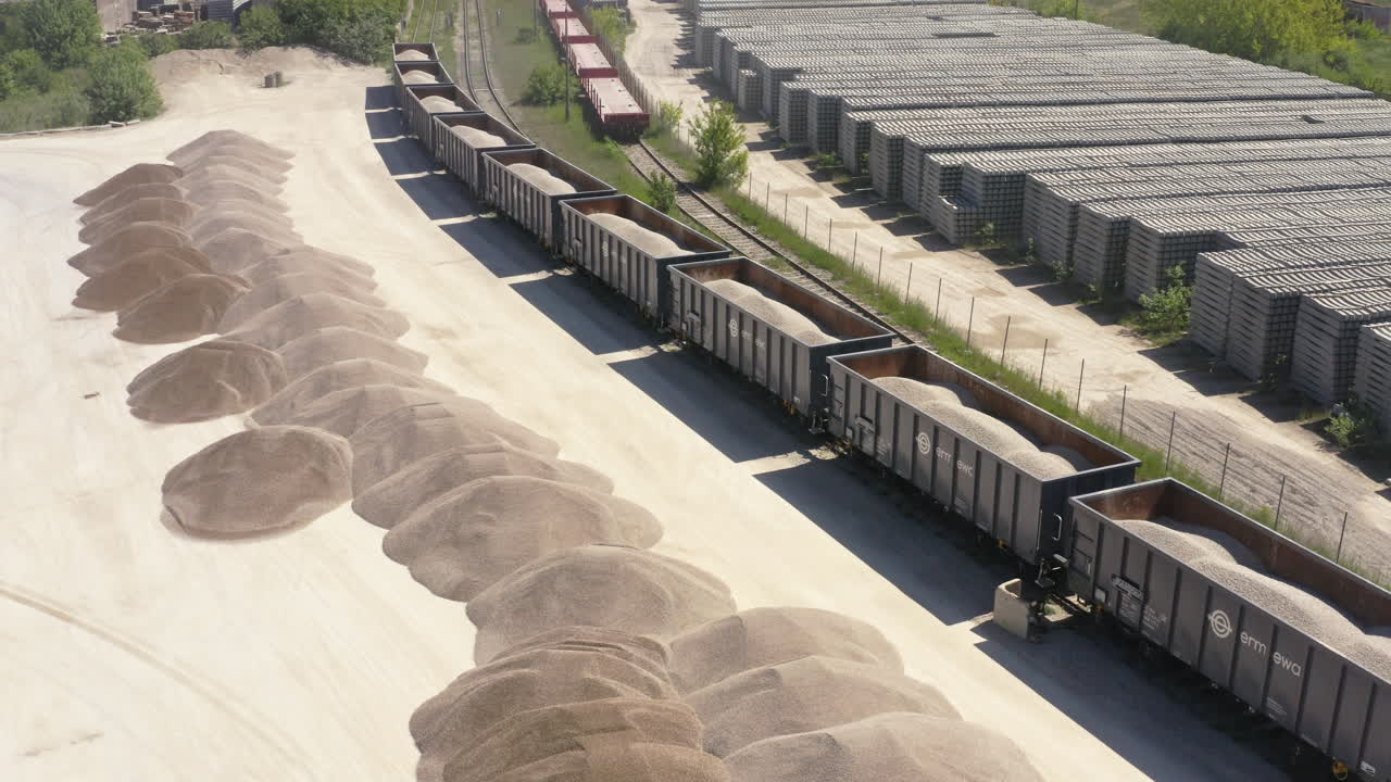 Long Freight Train Wagons Loaded With Gravel Next To Stockpile. - aerial shot