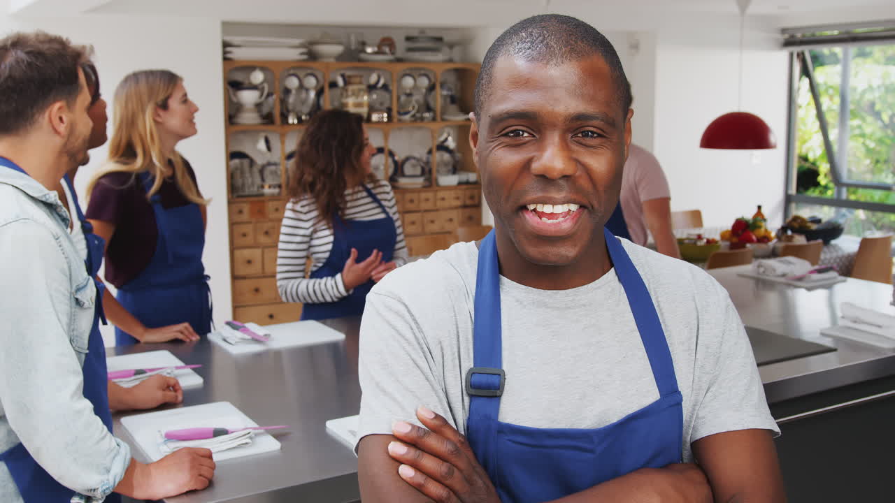 retrato de homem sorridente vestindo um avental participando de uma aula de culinária na cozinha