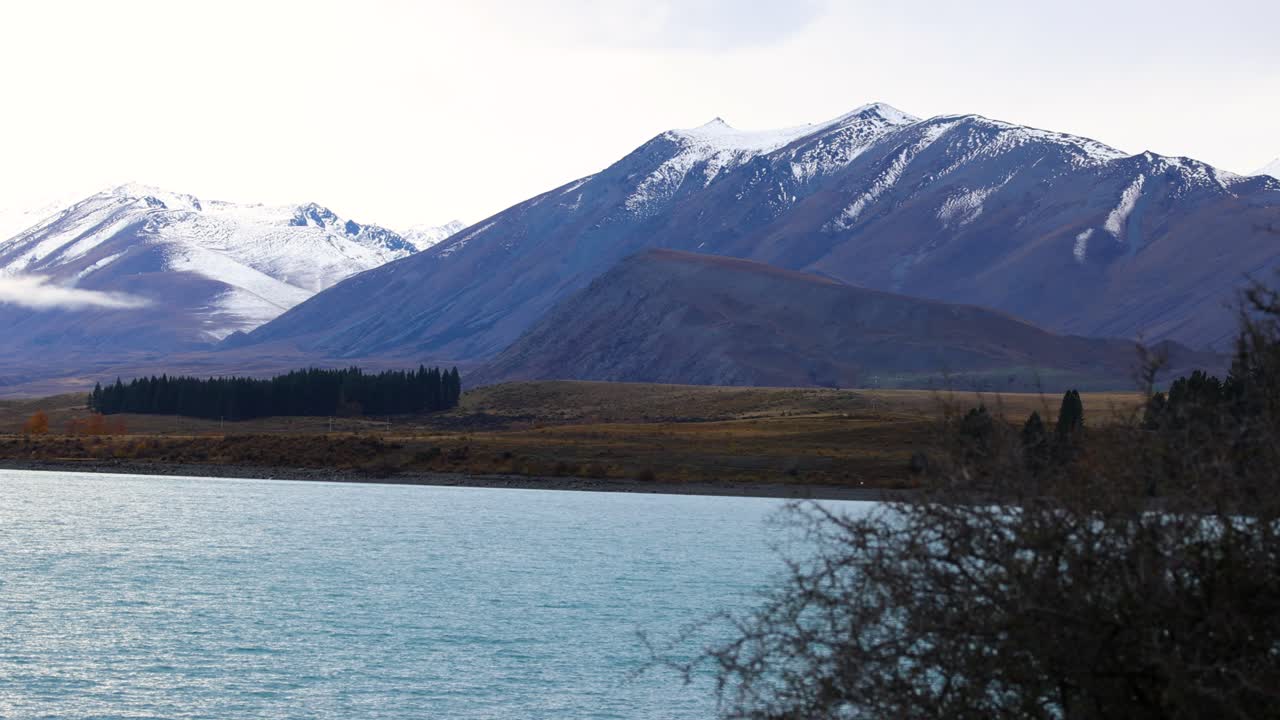 Tranquil view of Lake Tekapo with snow-covered mountains under soft lighting, capturing natural beauty and calmness