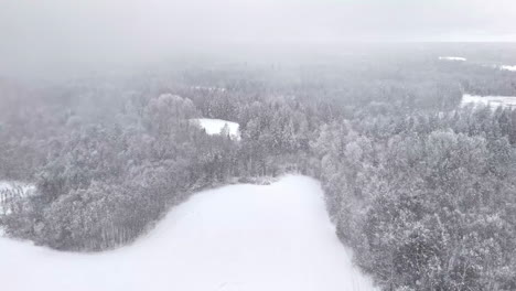 Frozen river or open field cutting through winter landscape, aerial of snow dusted terrain