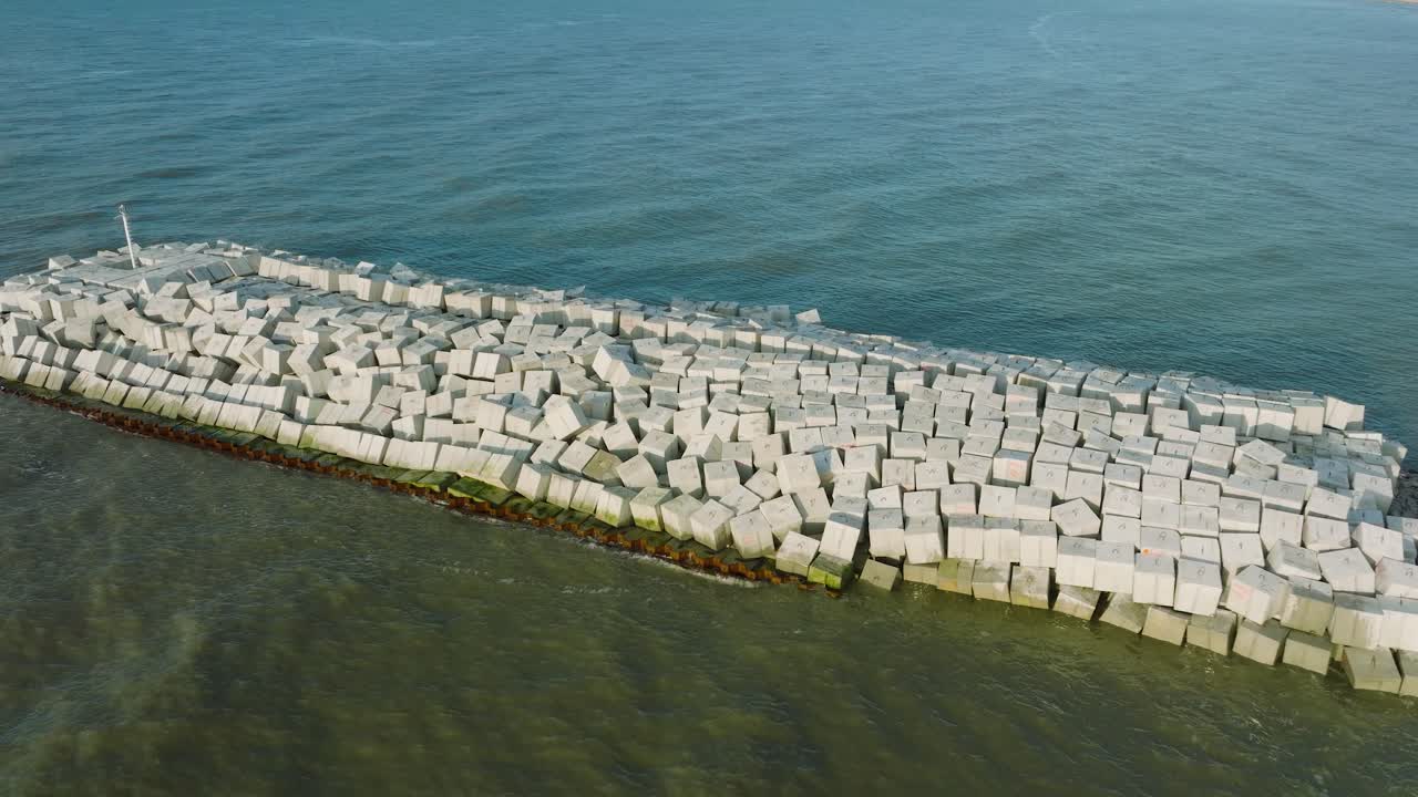 vista aérea de pájaro del muelle protector de piedra con bloques de hormigón y rocas en la costa del mar báltico en liepaja, letonia, fortaleciendo la playa contra la erosión costera, tiro de carro de drones moviéndose a la izquierda