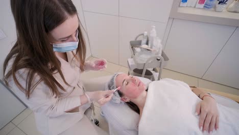 cosmetologist doing face treatment and applying face mask