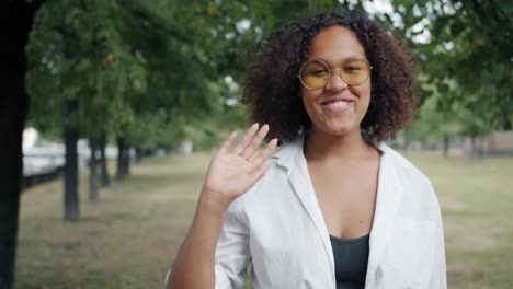 smiling woman waving in a park
