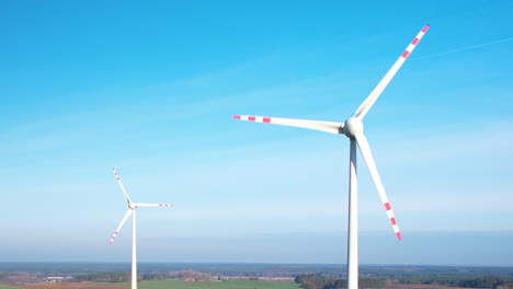 white wind turbine spin over the blue sky in polish countryside