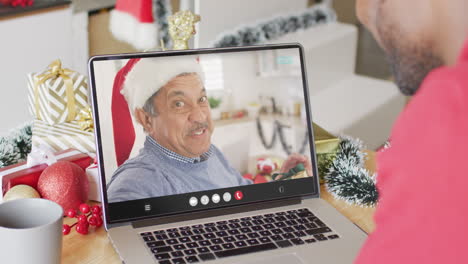 hombre afroamericano con sombrero de santa teniendo llamada de video portátil con hombre biracial feliz