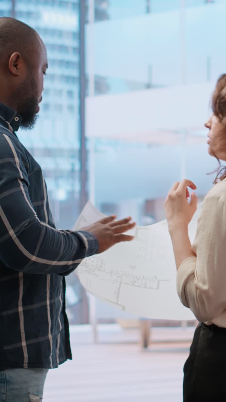 Architetti che discutono planimetrie edilizie in un ufficio moderno