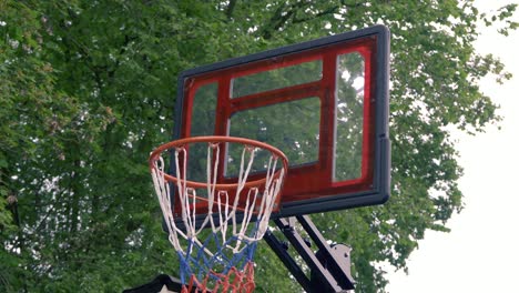 slowly zooming in shot of basketball hoop, throwing a ball and making one point