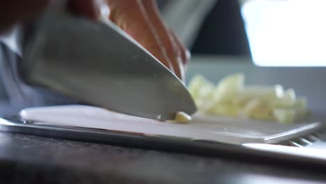 slowmo - chef cortando ajo con un cuchillo en la tabla de cortar en la cocina de la autocaravana - de cerca