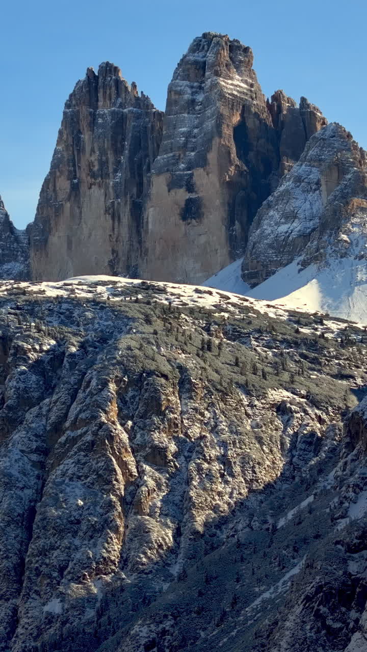 Aerial drone view of the Tre Cime di Lavaredo in the Sexten Dolomites of northeastern Italy with the blue sky on the background. Vertical