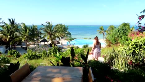 woman goes down stairs to an infinity pool with indian ocean view in luxurious hotel of zanzibar, tanzania