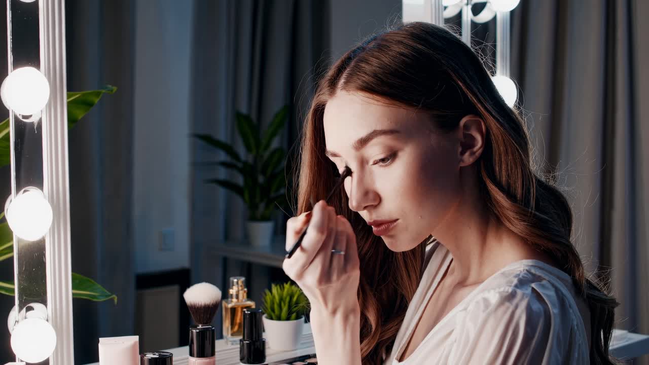 A video captures a woman with wavy hair at a vanity, viewed from behind