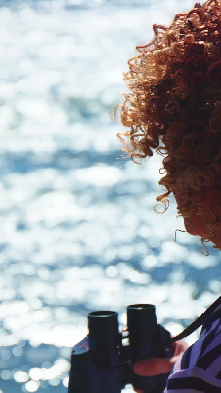 Woman with Curly Hair Looking Through Binoculars at the Ocean