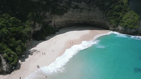 breathtaking aerial view of the beach and greenery covered cliffside at nusa penida kelingking
