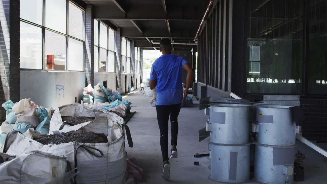 African american man wearing sports clothing jogging through an empty urban building