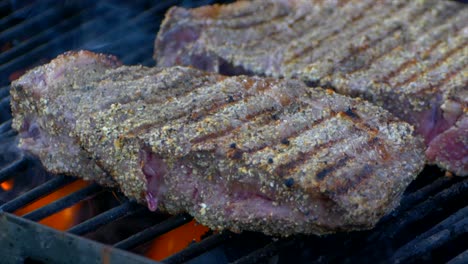 dos jugosos filetes de costilla cocinados a la parrilla mientras el fuego y las llamas se disparan hacia abajo