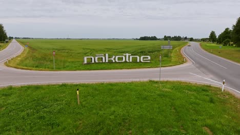 drone moves straight toward nākotne sign in latvia as vehicles drive past