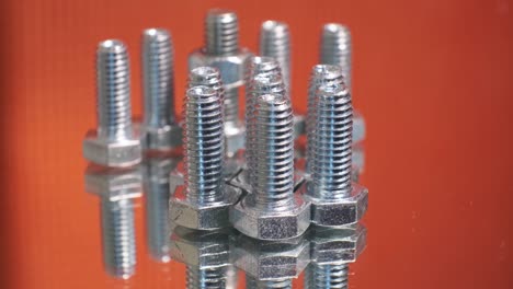 rotating group of galvanized metallic screws close-up. stainless steel bolts isolated on mirror reflective background.