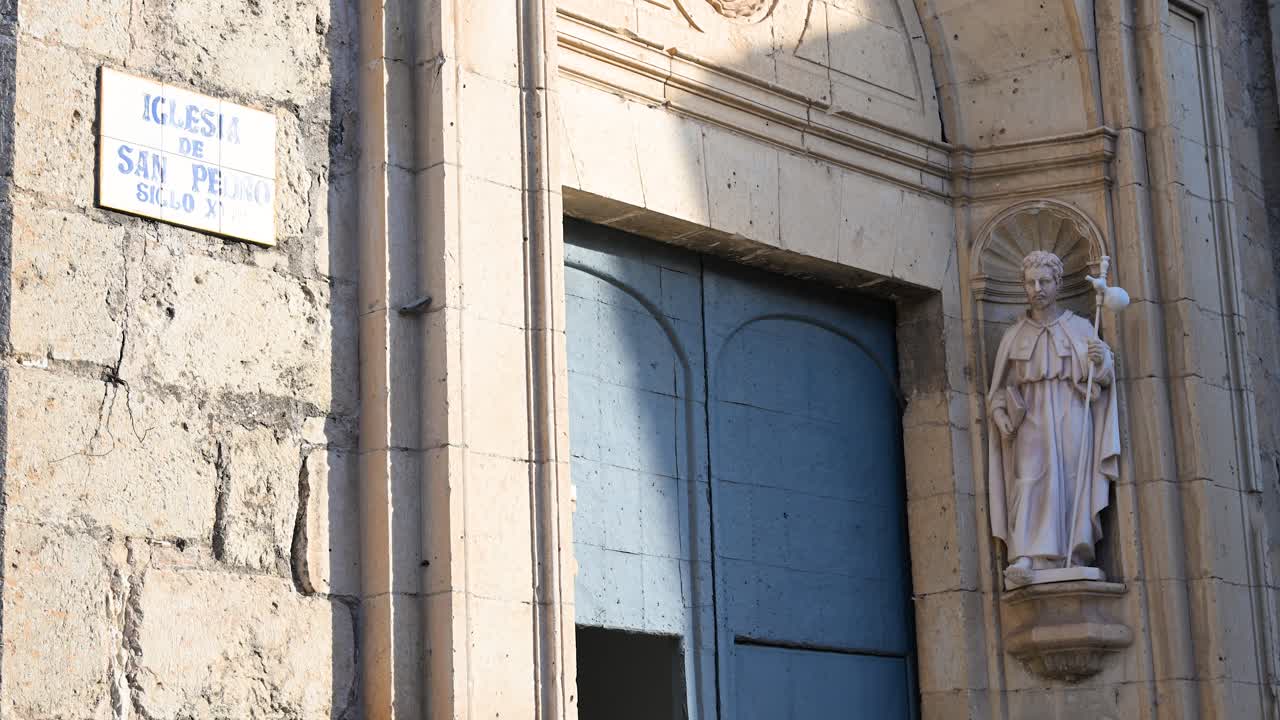 Sito storico di Cuenca: Ingresso alla Chiesa di San Pedro del XVIII secolo. Dettaglio della facciata in pietra, della porta blu e della statua del santo nella città UNESCO