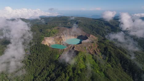 an aerial shot of blue volcanic crater lakes on a hilltop with a large forest