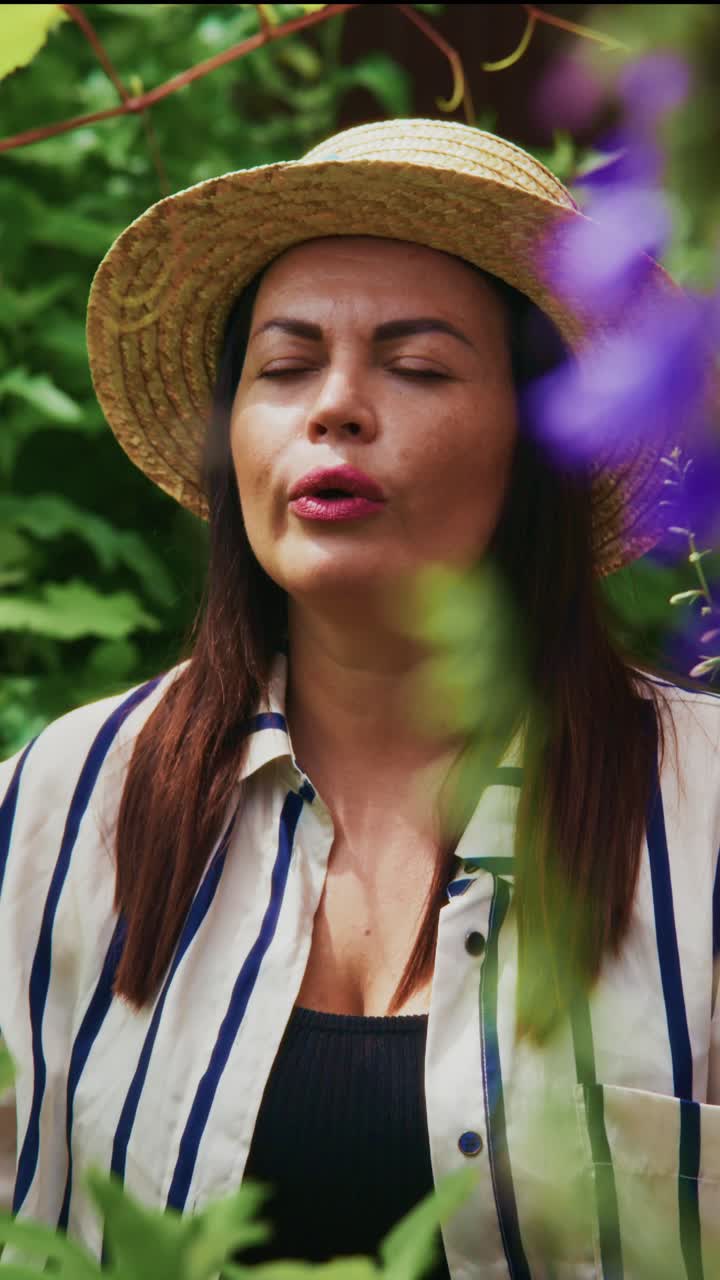 A Serene Moment: A Woman Enjoys Nature’s Beauty in a Lush Green Surrounding While Wearing Straw Hat and Striped Shirt, Capturing a Blissful Connection with the Outdoors