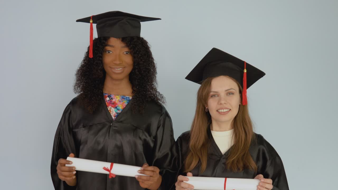 jóvenes mujeres afroamericanas y caucásicas están en asignación y tienen diplomas horizontales