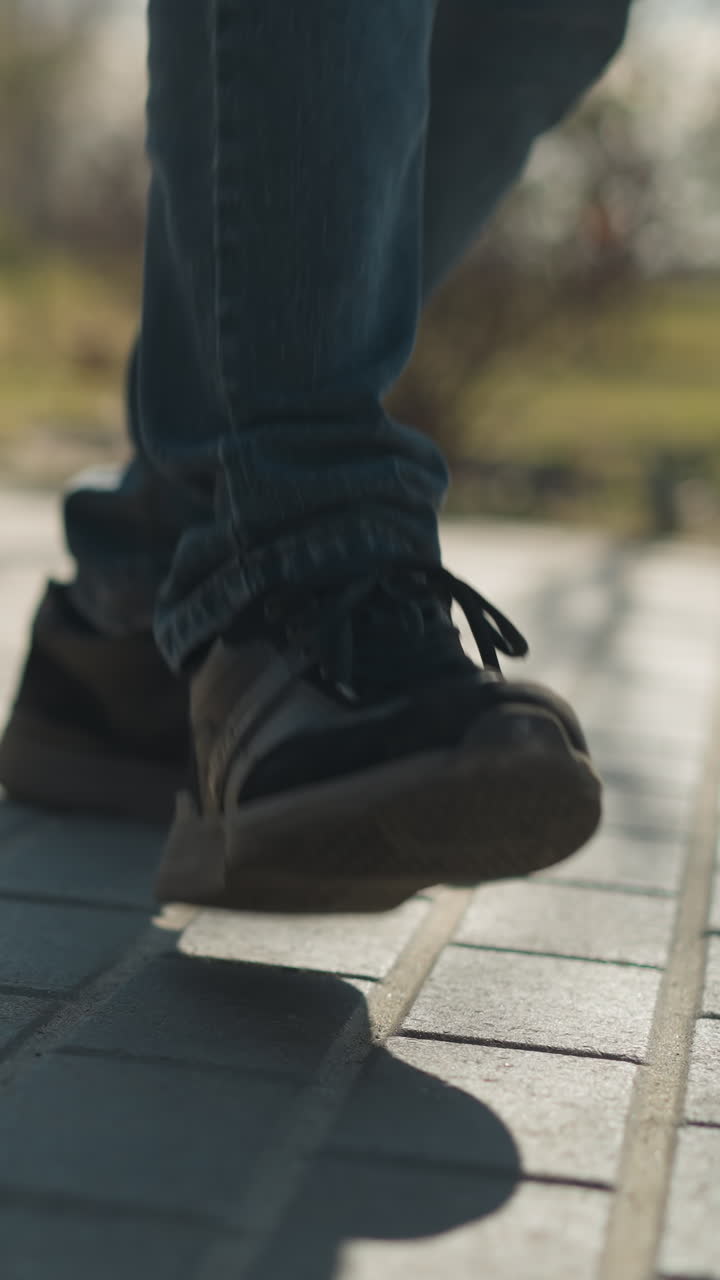 un primer plano de las piernas de dos personas, un adulto y un niño, mientras golpean su pierna derecha juntos en un camino pavimentado, ambos llevan vaqueros azules y botas robustas