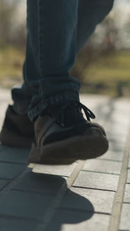 un primer plano de las piernas de dos personas, un adulto y un niño, mientras golpean su pierna derecha juntos en un camino pavimentado, ambos llevan vaqueros azules y botas robustas
