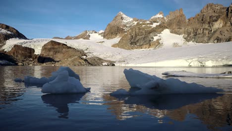 peaceful morning scene at the glacial lake next to claridenfirn glacier in uri, swizerland with the alpine peaks reflected and icebergs floating in the foreground