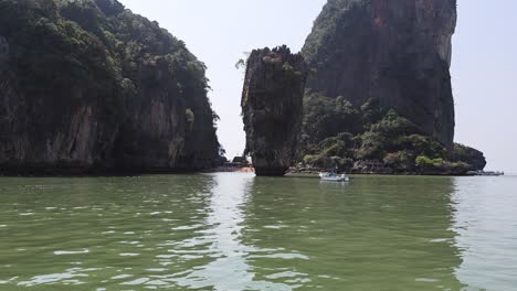 barcos navegando cerca de los altos acantilados de piedra caliza en phuket