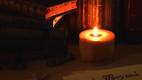 close up background of an ancient library, next to a frieplace, with old books, old paper, stones, and a candle with flickering flame