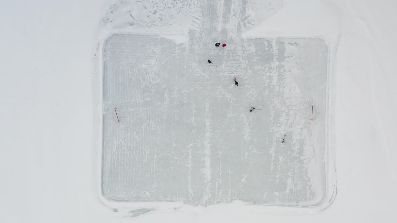 arriba hacia abajo, gente jugando hockey sobre hielo en una pequeña pista al aire libre en un lago congelado