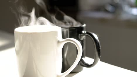 tazas de café caliente al vapor en la luz de la mañana temprano en la cocina
