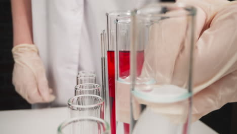 Scientist-in-gloves-takes-test-tube-with-red-liquid-in-lab